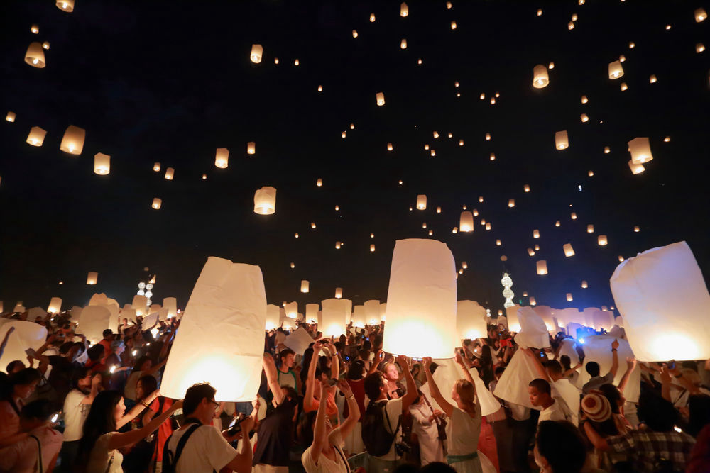 Foto: Gruppe von Leuten lässt Laternen mit Lichtlein in den Nachthimmel steigen